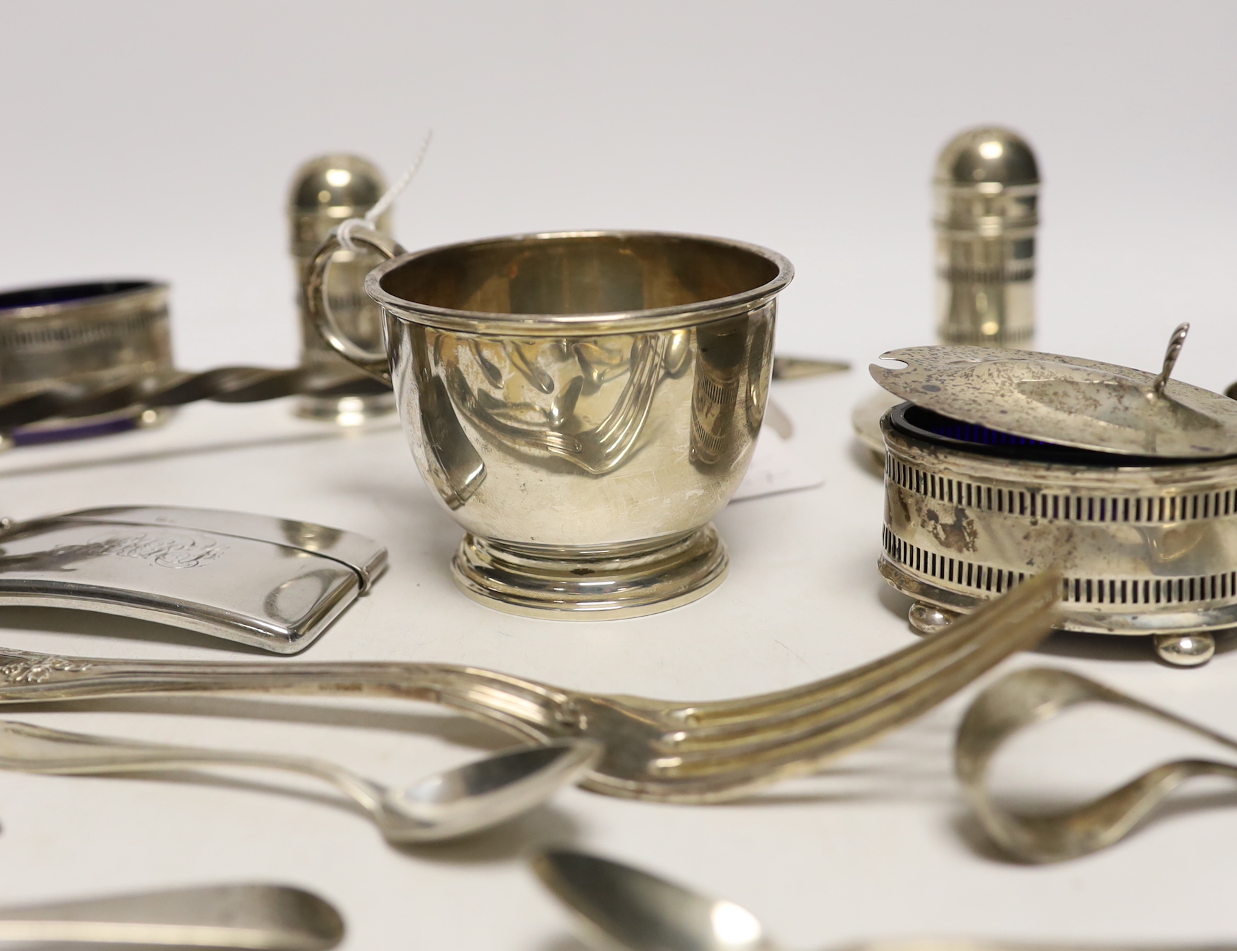 A 1930's silver single handled cup, a four piece silver condiment set, Edwardian silver card case, pair of silver pepperettes, napkin rings, sundry small flatware including sterling etc.